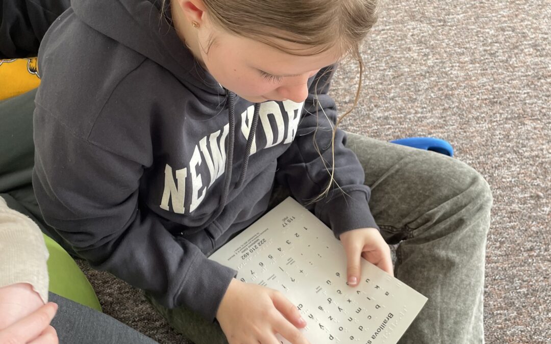 Dívka si prohlíží předtisk Braillovy abecedy.