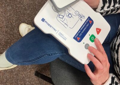 Účastnice kurzu drží v rukou defibrilátor a seznamuje se s jeho jednotlivými částmi.