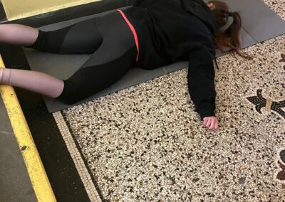 Figurantka Life Support leží pod schody a simuluje bezvědomí po pádu.