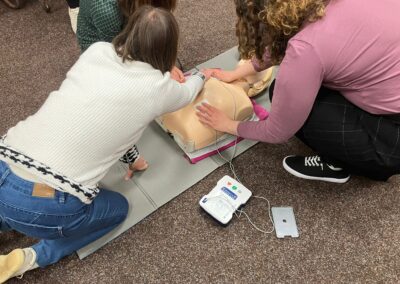 Anička a Kačí u figuríny nacvičují použití defibrilátoru.