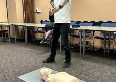 Lektor Life Support stojí u figuríny a vysvětluje, jak poskytnout první pomoc člověku v bezvědomí.